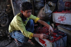 ごみ処理場でバッテリーの修理の仕事をする10歳の男の子。（バングラデシュ）