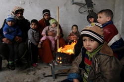 破壊された自宅で、暖を取る家族。（パレスチナ）