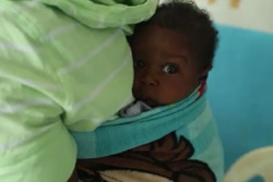 出生登録を行う移動チームから出生登録書の発行を待つ3カ月の赤ちゃん。