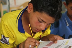 ザータリ難民キャンプの中にあるドロップ・イン・センターで算数の問題を解くアハメドくん。