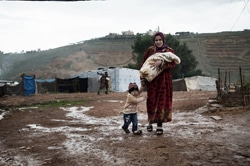 レバノンの非公式テント居住区に身を寄せるシリア難民の親子。