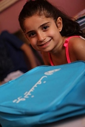 アレッポの学校でユニセフの支援物資の通学かばんを受け取り、笑顔を見せる1年生の女の子。