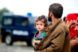 ギリシャとの国境を接するマケドニア旧ユーゴスラビア共和国のゲヴゲリヤ近郊で、父親に抱かれる女の子。