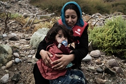 エーゲ海の北東部レスボス島の海岸で、幼い女の子を抱きしめるシリア出身の女性。