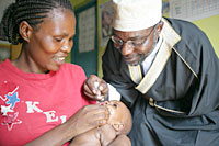 写真：コンゴ民主共和国：子どもにポリオワクチンを投与するコミュニティの宗教リーダー