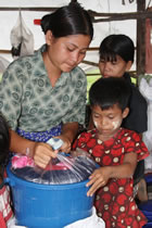 ファミリーキットを受け取って開ける18歳と8歳の女の子。二人とも、両親を災害で亡くしました。今二人は、家族を失った子どもたちのために設置された、エーヤワンディ管区内のティンガンジ村の仮設施設で避難生活を送っています。