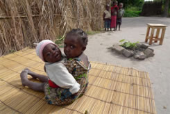 ザンビアのチルンバ村にある自宅の前で、弟（生後8ヵ月）を抱く女の子（4歳）