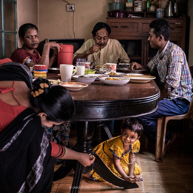 A girl hides under the family dinner table, Bangladesh