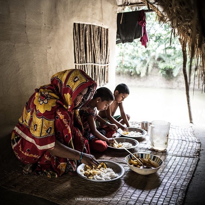 A woman eats lunch with her daughters, Bangladesh