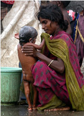栄養不良の幼児の体を洗う母親＝バラート・ナガール・スラム